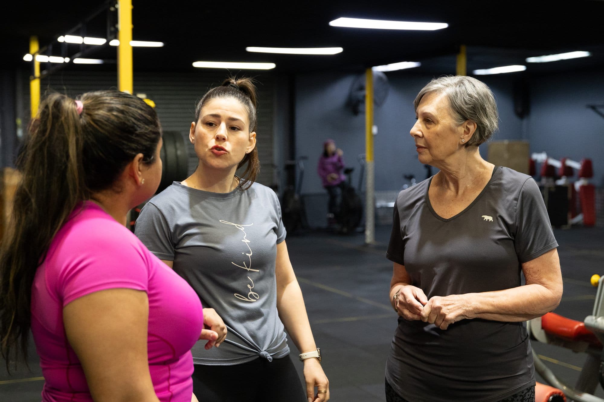 Alex talking with two clients on the gym floor, explaining something between sets