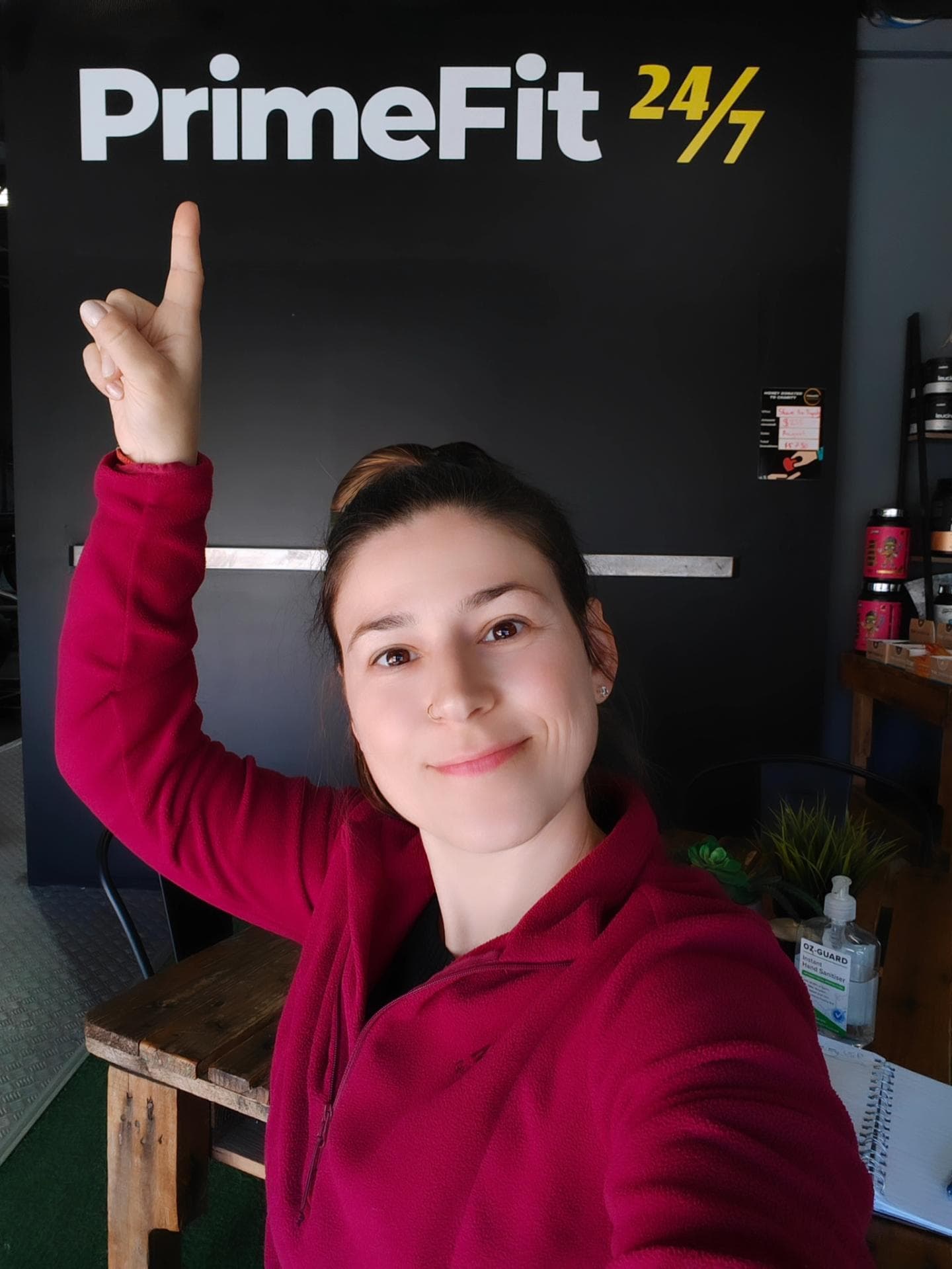 Alex pointing up at the Prime Fit 24/7 sign inside the gym