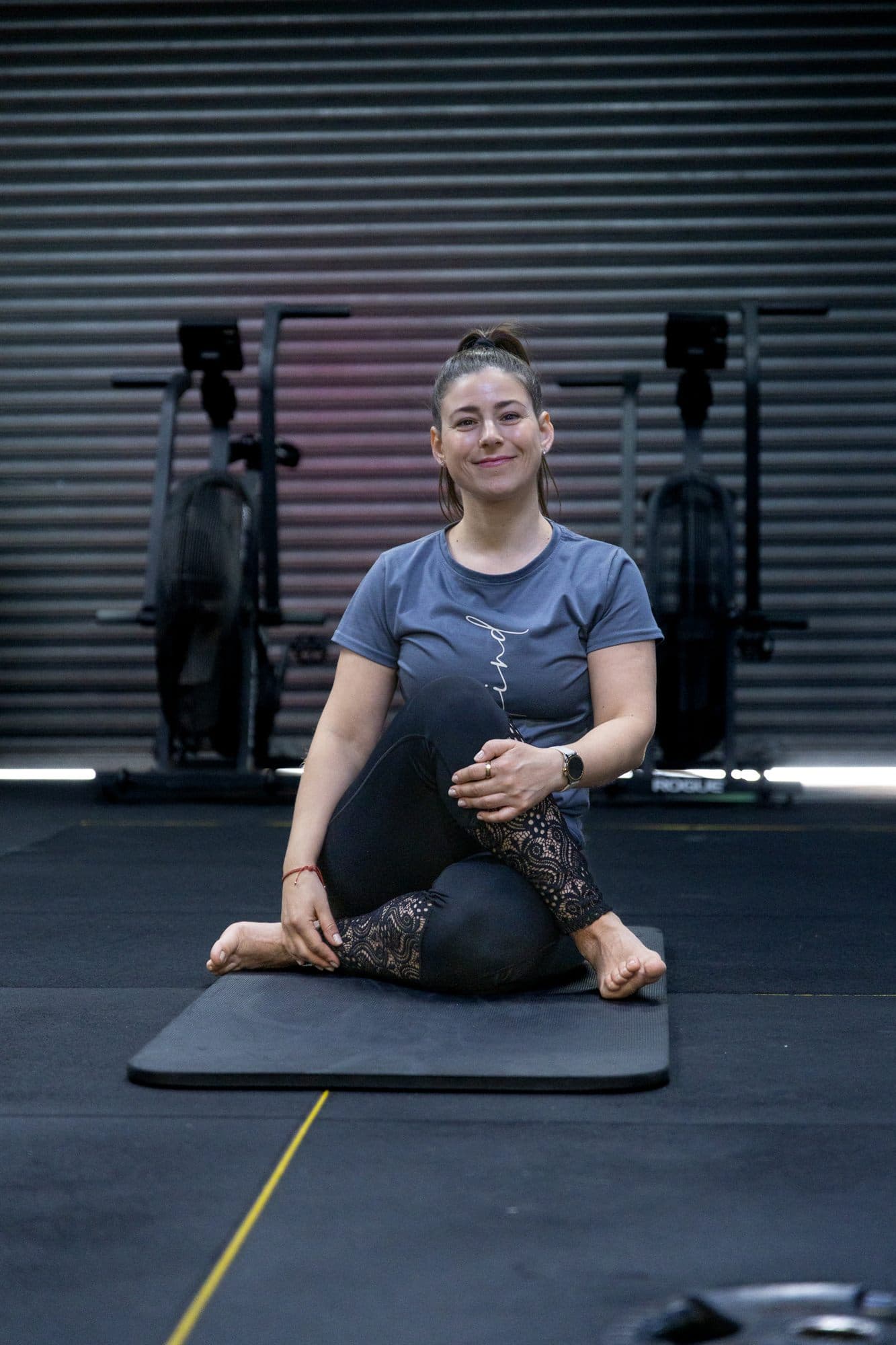 Alex sitting on a mat on the gym floor, smiling